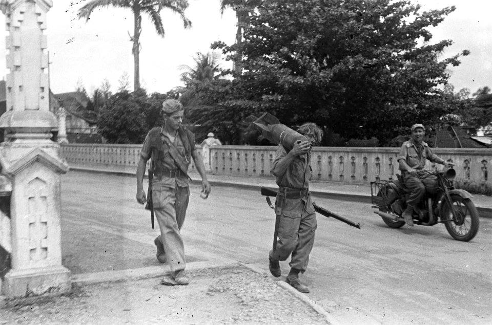 Twee soldaten, waarvan één met een vliegtuigbom over de schouder lopen over ee…, Bestanddeelnr 5235