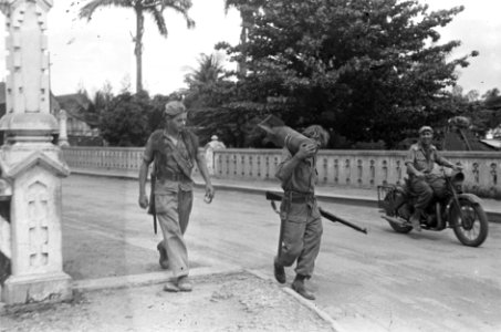 Twee soldaten, waarvan één met een vliegtuigbom over de schouder lopen over ee…, Bestanddeelnr 5235