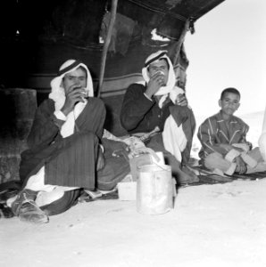 Twee volwassen koffiedrinkende bedoeienen in een tent met een jongen, Bestanddeelnr 255-3484 photo