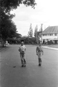 Twee militairen op rolschaatsen op een brede straat. Daarachter een groot huis w, Bestanddeelnr 6308