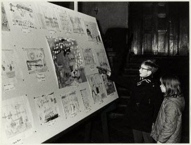 Twee onbekende kinderen bekijken tekeningen op een tentoonstelling van kindertekeningen in de Gravenzaal op het stadhuis