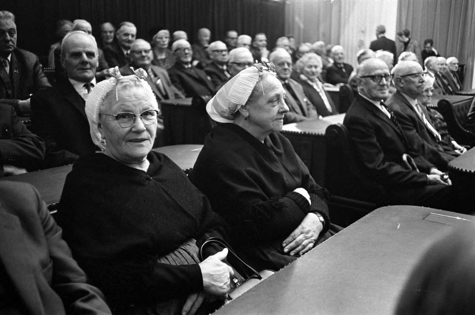 Twee Scheveningse vissersvrouwtjes zittend in de banken die gevuld zijn met mens, Bestanddeelnr 918-4793