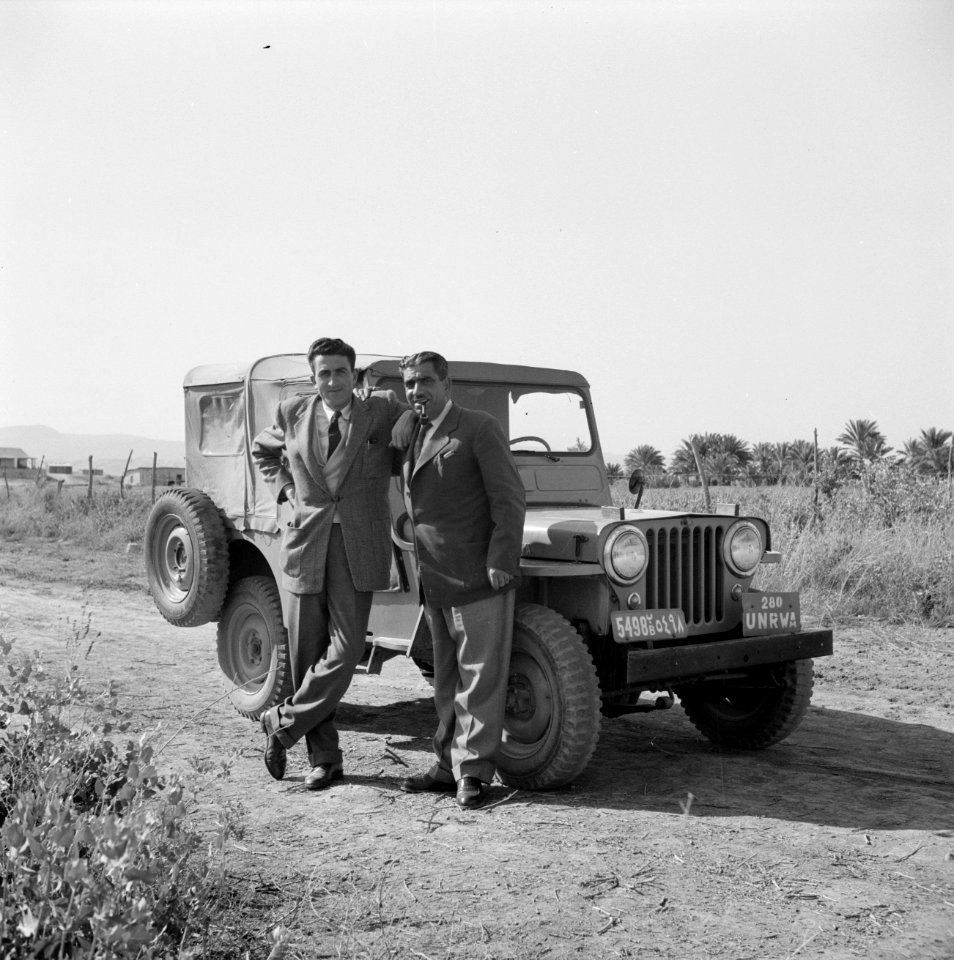 Twee personen behorende tot de U.N. Refugee Organization voor hun jeep, Bestanddeelnr 255-5629