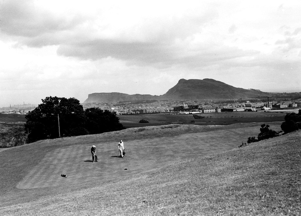 Twee mannen op een golfbaan, met de stad op de achtergrond, Bestanddeelnr 252-1268