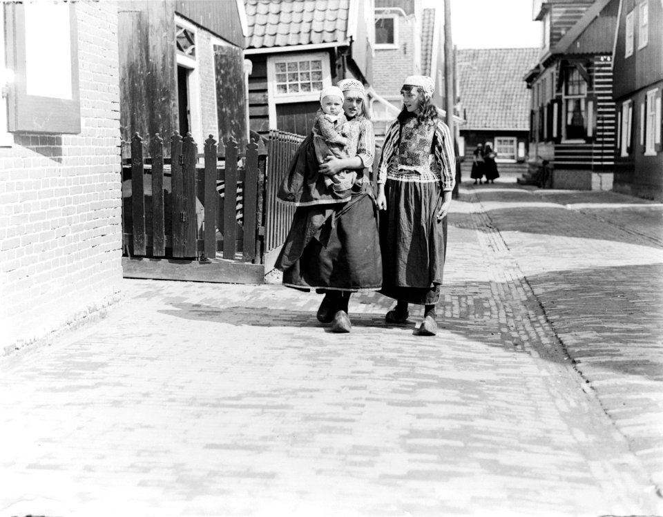 Twee meisjes in klederdracht, waarvan een met een peuter op haar arm, eveneens i, Bestanddeelnr 252-0692