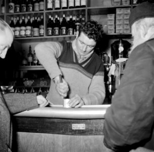 Twee mannen staan aan de bar terwijl de barkeeper een blikje opent, Bestanddeelnr 252-9499