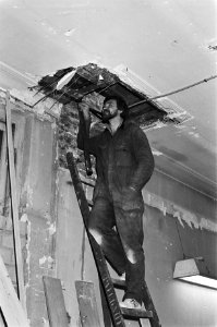 Tussen plafond van pand aan Amsterdamse Rokin, werkman kiijkt in het gat van het, Bestanddeelnr 931-3279