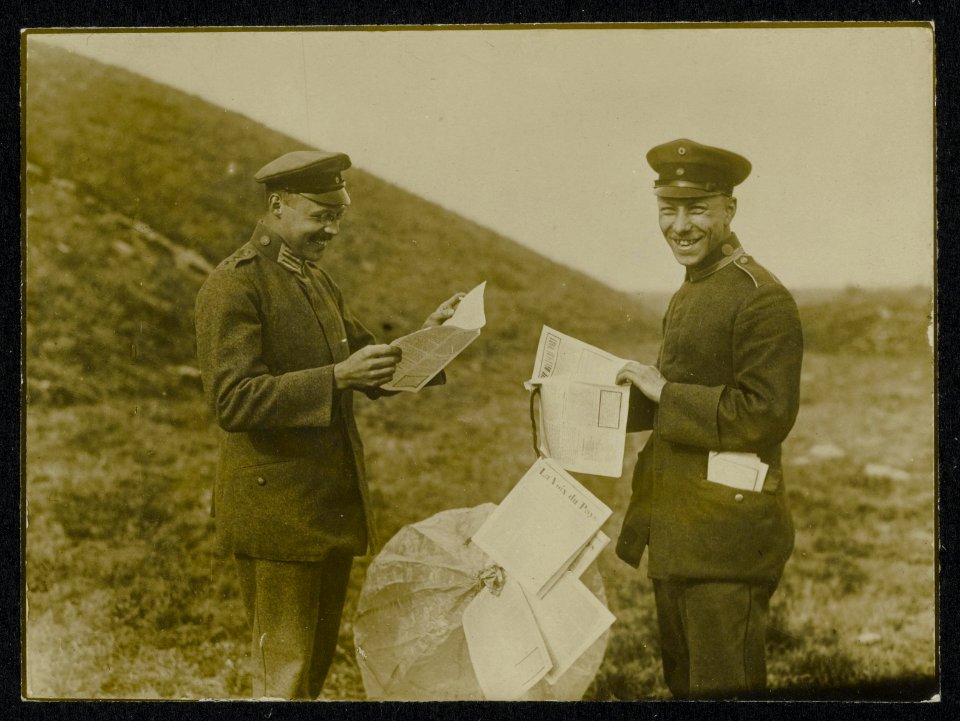 Twee Duitse militairen lezen in een per parachute uitgeworpen blad La Voix du P, Bestanddeelnr 158-0320