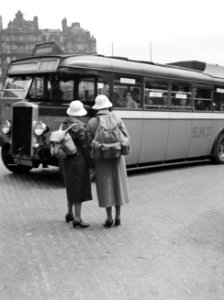 Twee dames met rugzakken wachten op een voorbijrijdende autobus, Bestanddeelnr 252-1334