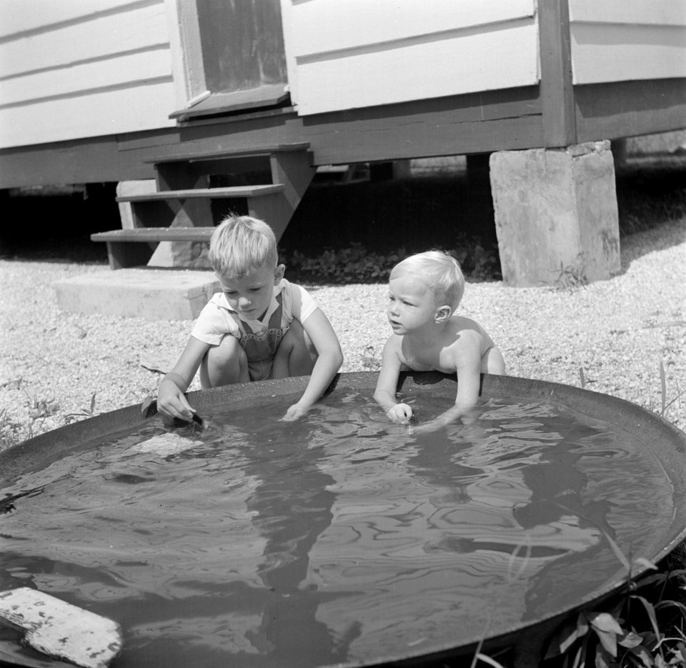 Twee blonde jongetjes bij een bak met water in Nickerie in Suriname, Bestanddeelnr 252-7024