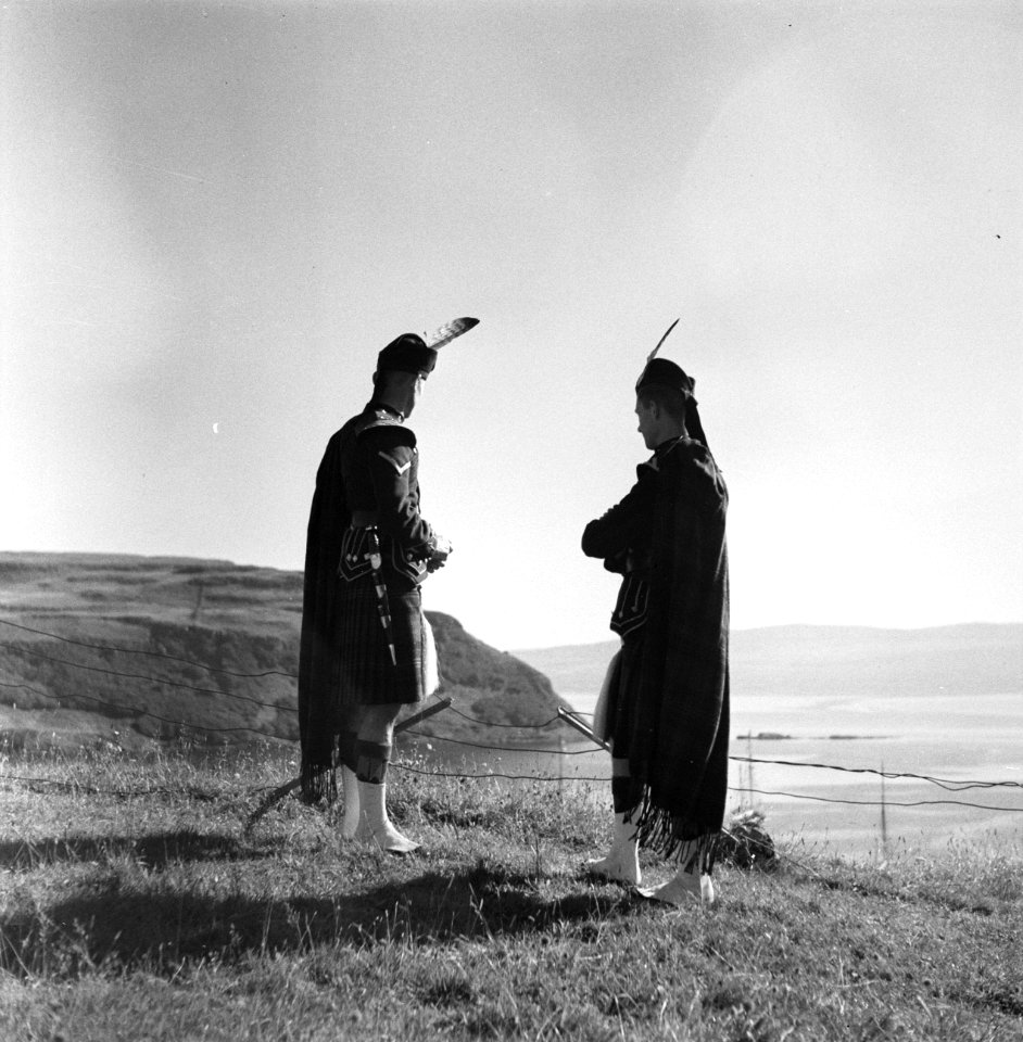 Twee deelnemers aan de Highland Games kijken uit over zee, Bestanddeelnr 254-2837