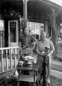 Two lady golfers beside a table with trophies outside Llandrindod Wells Golf Club pavilion (1294836)