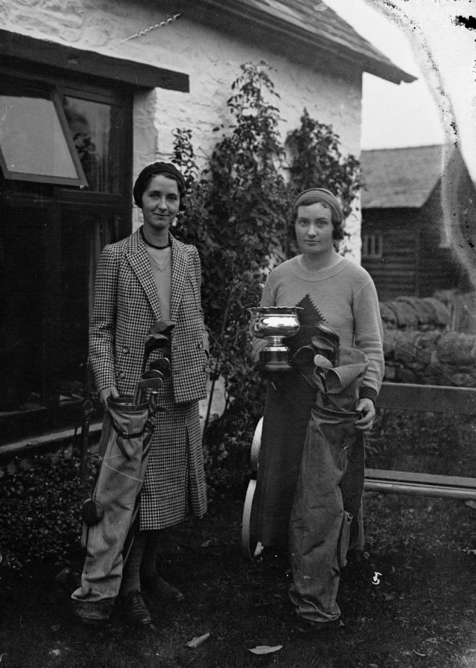 Two lady golfers with clubs, one holding a trophy (1293465)