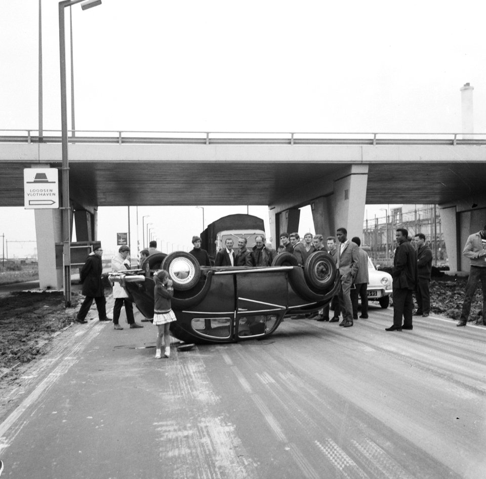 Omstanders bekijken de op zijn kop liggende Volkswagen Kever, Bestanddeelnr 919-6026