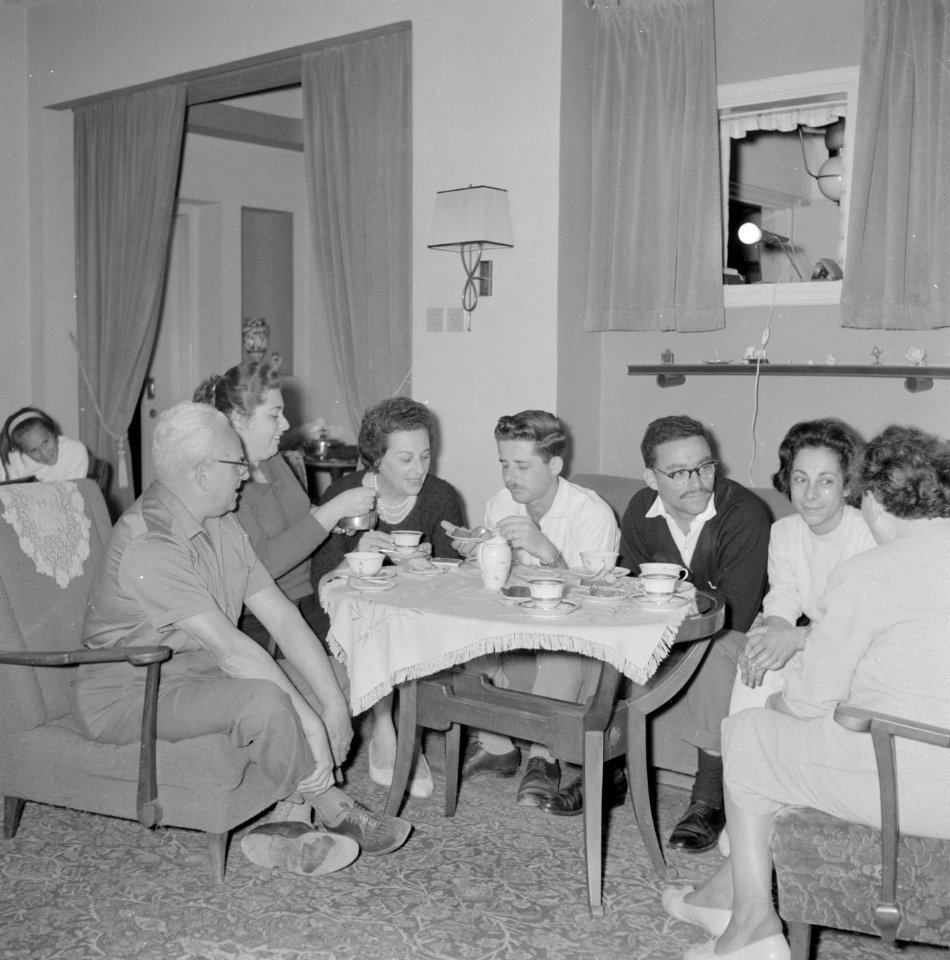 Onbekend gezelschap mannen en vrouwen rond een tafel gezeten terwijl er thee wor, Bestanddeelnr 255-4316