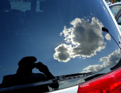 Photo of reflection in rear window of car in a parking lot