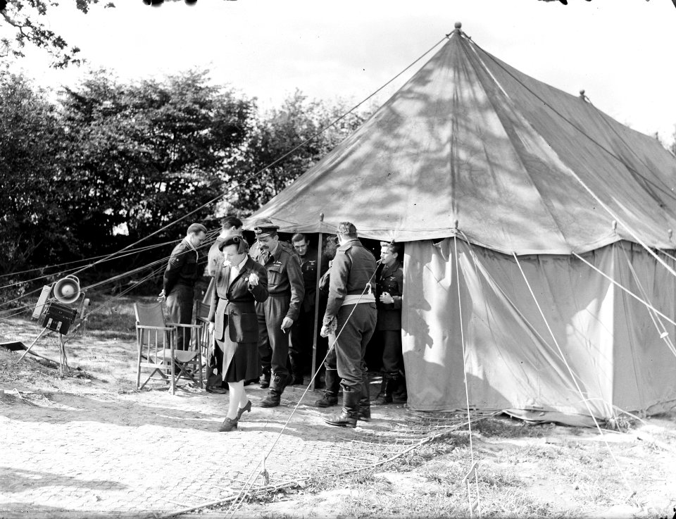 Prinses Juliana verlaat, een sigaret rokend, een tent, achter haar de Squadron L, Bestanddeelnr 934-8839