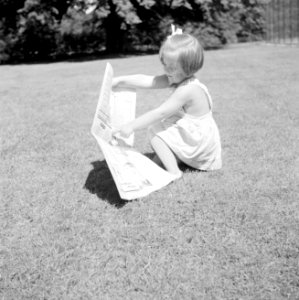 Prinses Margriet speelt met een krant op het grasveld bij het zomerhuisje, Bestanddeelnr 255-7864