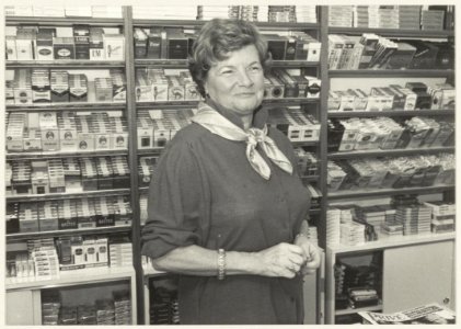 Portret van Greet Bartels achter de toonbank van haar sigarenwinkel. NL-HlmNHA 54013870