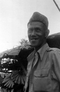 Portret van Indonesische man met peci. Achter hem zijn trossen bananen zichtbaar, Bestanddeelnr 6510