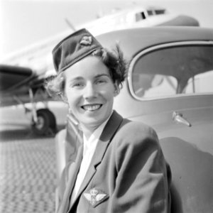 Portret van een KLM stewardess leunend tegen een auto met op de achtergrond een , Bestanddeelnr 255-8962