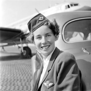 Portret van een KLM stewardess leunend tegen een auto met op de achtergrond een , Bestanddeelnr 255-8961