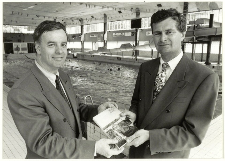 Presentatie jaarboek Haerlem 1991 aan wethouder P. Schouten door W.J. van Luyken, voorzitter vereniging Haerlem in de zwemzaal van het Sportfondsenbad, ziende naar het zuidoosten. NL-HlmNHA 54037590