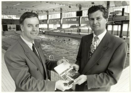 Presentatie jaarboek Haerlem 1991 aan wethouder P. Schouten door W.J. van Luyken, voorzitter vereniging Haerlem in de zwemzaal van het Sportfondsenbad, ziende naar het zuidoosten. NL-HlmNHA 54037590