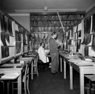 Rechts vermoedelijk een röntgenoloog voor een wand met röntgenfoto's en links ee, Bestanddeelnr 252-9129