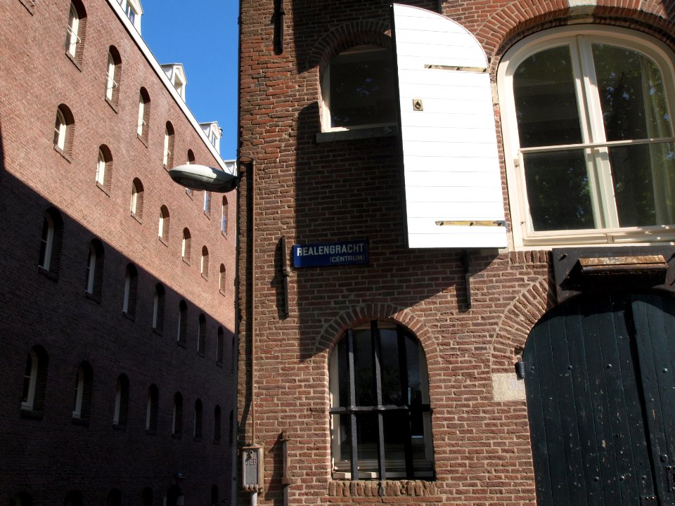 Realengracht straatnaambord op pakhuis met raam met tralies