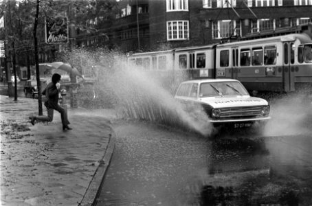 Regen in Amsterdam. Auto laat water van plas hoog opspatten, Bestanddeelnr 922-9384