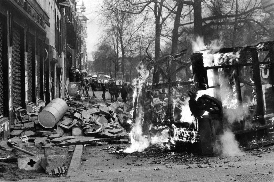 Puin en een brandende barricade voor het pad met op de achtergrond de ME, Bestanddeelnr 931-3108