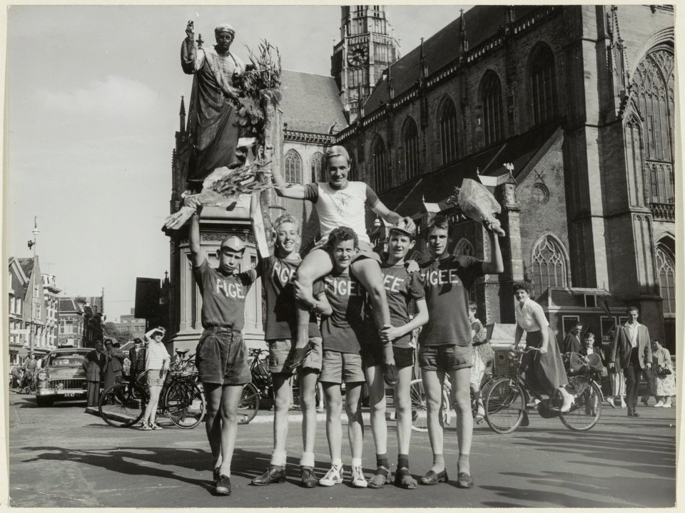 Rob van Straaten, winnaar van de Muggenronde op de schouders van zijn ploeggenoten voor het standbeeld van L.J. Coster. NL-HlmNHA 54004317