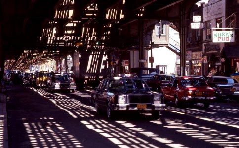 Roosevelt-avenue-queens-nyc cars driving-under-elevated-railway-line 1980s