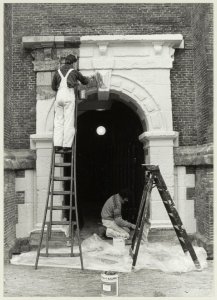 Restauratie van de toren van de Nieuwe Kerk. Schilders leggen de laatste hand aan het portaal van de kerk. Rechts Henk Pas, links Dirk van der Meij van Schildersbedrijf Rijs. NL-HlmNHA 54011447