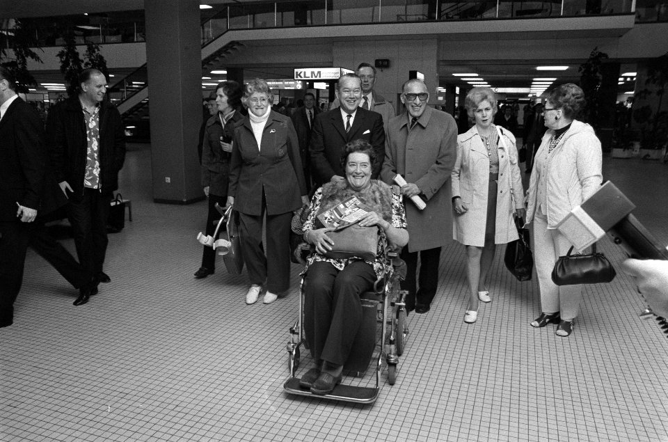 Reumapatienten vertrekken voor vakantie van Schiphol, Max Tailleur met patiente , Bestanddeelnr 925-2148