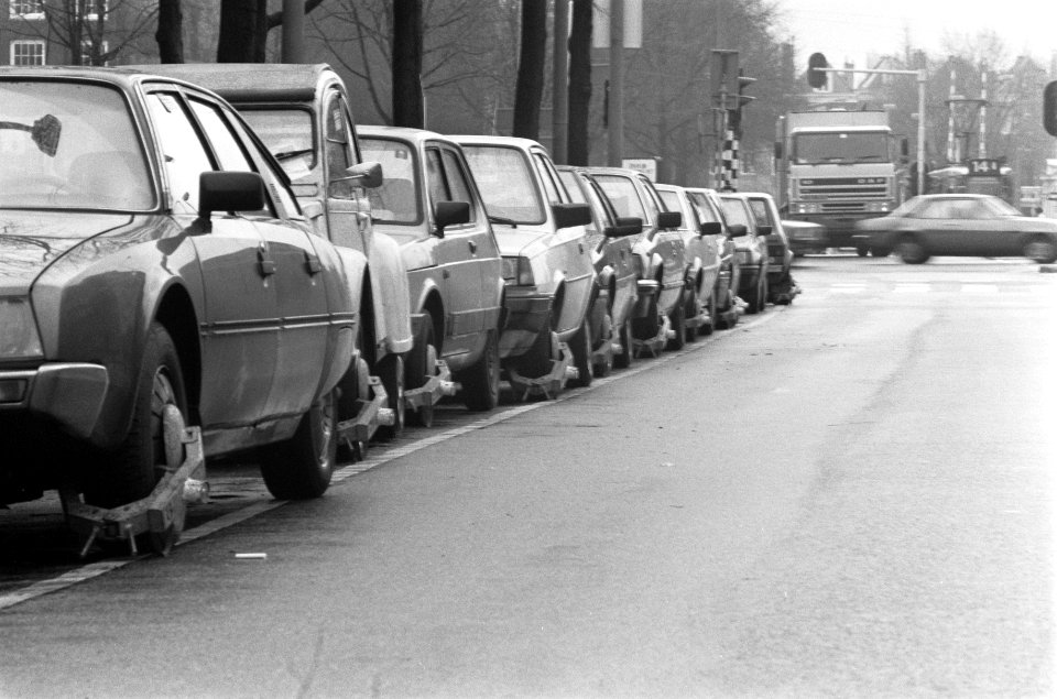 Rij geparkeerde autos met de wielklem in Jodenbreestraat in Amsterdam, Bestanddeelnr 934-1771