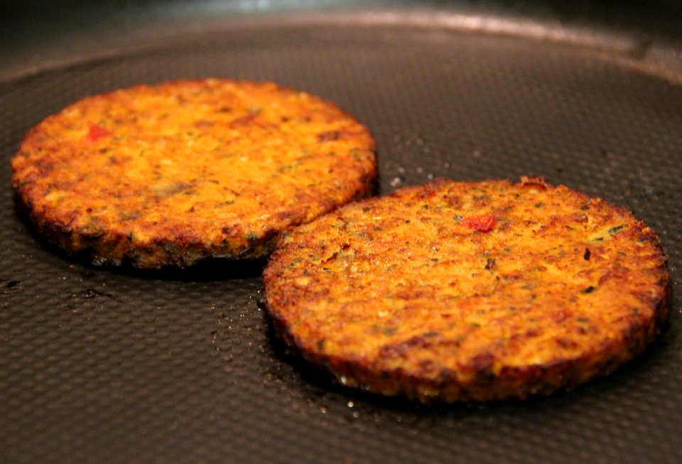 Two Morningstar Farms Tomato & Basil Pizza veggie burgers on a frying pan