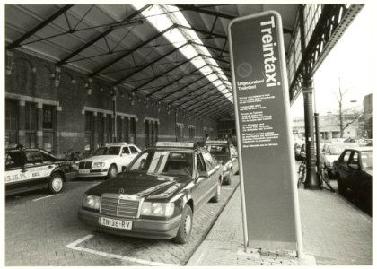 Treintaxi's op de voormalige taxistandplaats onder de rijtuigkap op het Stationsplein. NL-HlmNHA 54032251