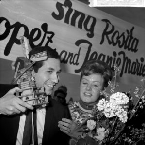 Trini Lopez op Schiphol krijgt een molentje aangeboden door Volendamse schone, Bestanddeelnr 916-0273