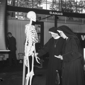 Vakbeurs Medica 65 in expohal te Hilversum, verpleegste bij geraamte, Bestanddeelnr 918-2229