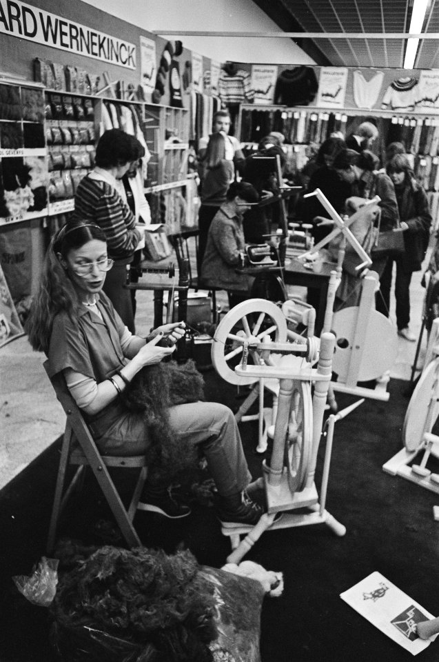 Vakbeurs Creatief met vooraan een vrouw achter een spinnewiel, Bestanddeelnr 931-3101