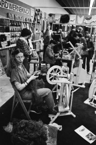 Vakbeurs Creatief met vooraan een vrouw achter een spinnewiel, Bestanddeelnr 931-3101