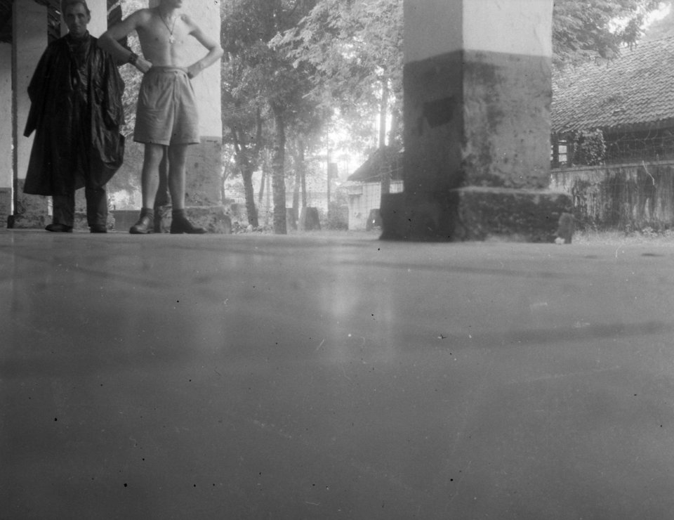 Veranda. Twee mannen, een in regencap, een met ontbloot bovenlijt, Bestanddeelnr 12439
