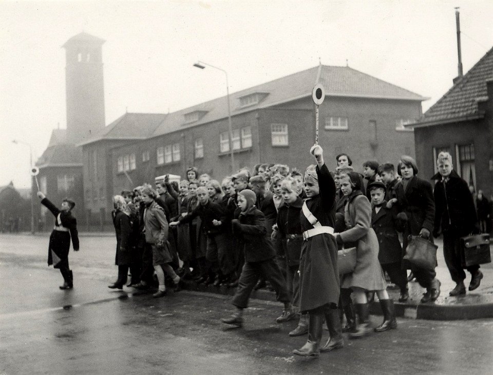 Veilig verkeer. Verkeersbrigadiertjes, met Endlich-arm, brengen schoolgaande kinderen veilig over de gevaarlijke Rijksstraatweg nabij de Vergierdeweg. Aangekocht in 1977 van United Photos de, NL-HlmNHA 54004512