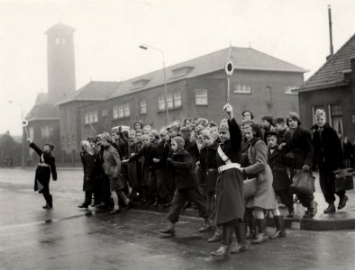 Veilig verkeer. Verkeersbrigadiertjes, met Endlich-arm, brengen schoolgaande kinderen veilig over de gevaarlijke Rijksstraatweg nabij de Vergierdeweg. Aangekocht in 1977 van United Photos de, NL-HlmNHA 54004512