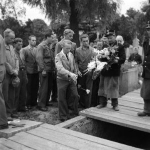 Uitvaart aanwezigen strooien bloemen in het graf, Bestanddeelnr 900-3471