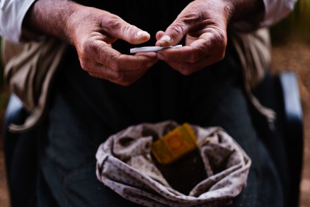 Views in June of 2019 of an Ezidi man in Sardashte Camp for displaced Ezidis rolling a cigarette with tobacco grown nearby atop Shingal mountain 33