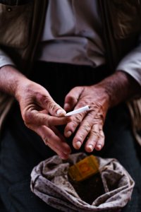 Views in June of 2019 of an Ezidi man in Sardashte Camp for displaced Ezidis rolling a cigarette with tobacco grown nearby atop Shingal mountain 35