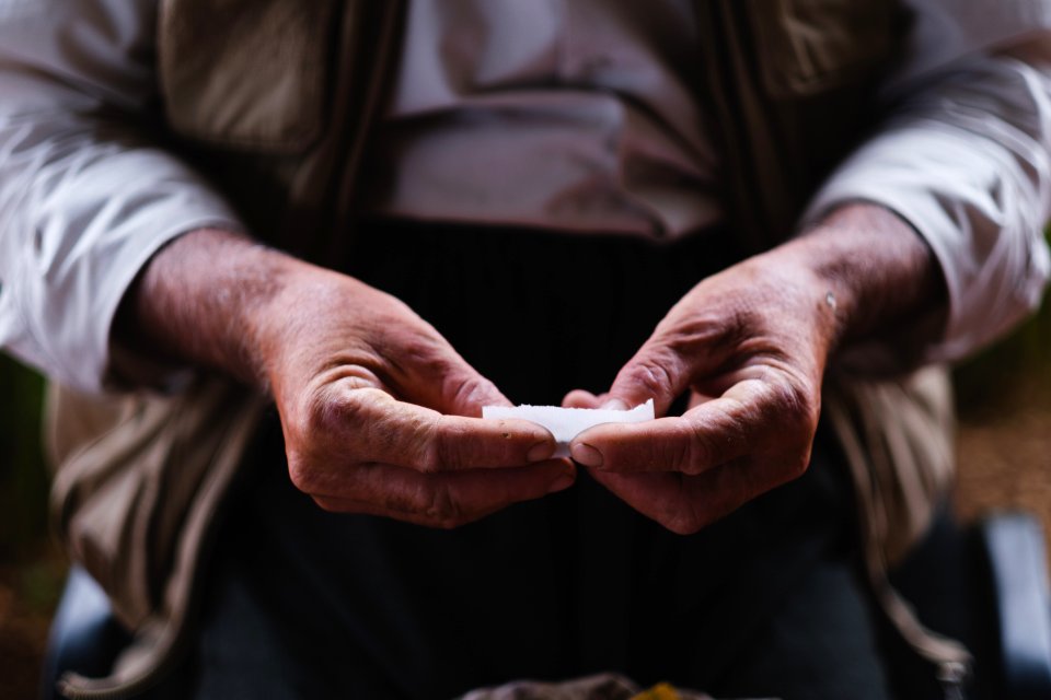 Views in June of 2019 of an Ezidi man in Sardashte Camp for displaced Ezidis rolling a cigarette with tobacco grown nearby atop Shingal mountain 32